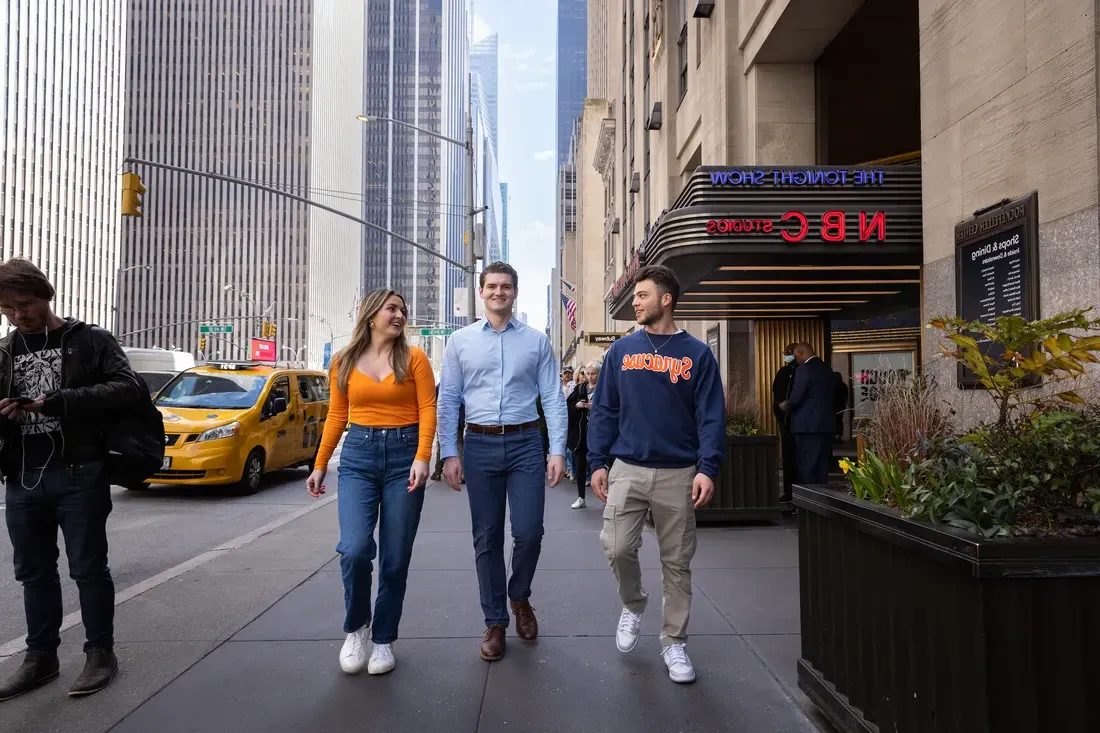 Three people walking down the street in New York City.