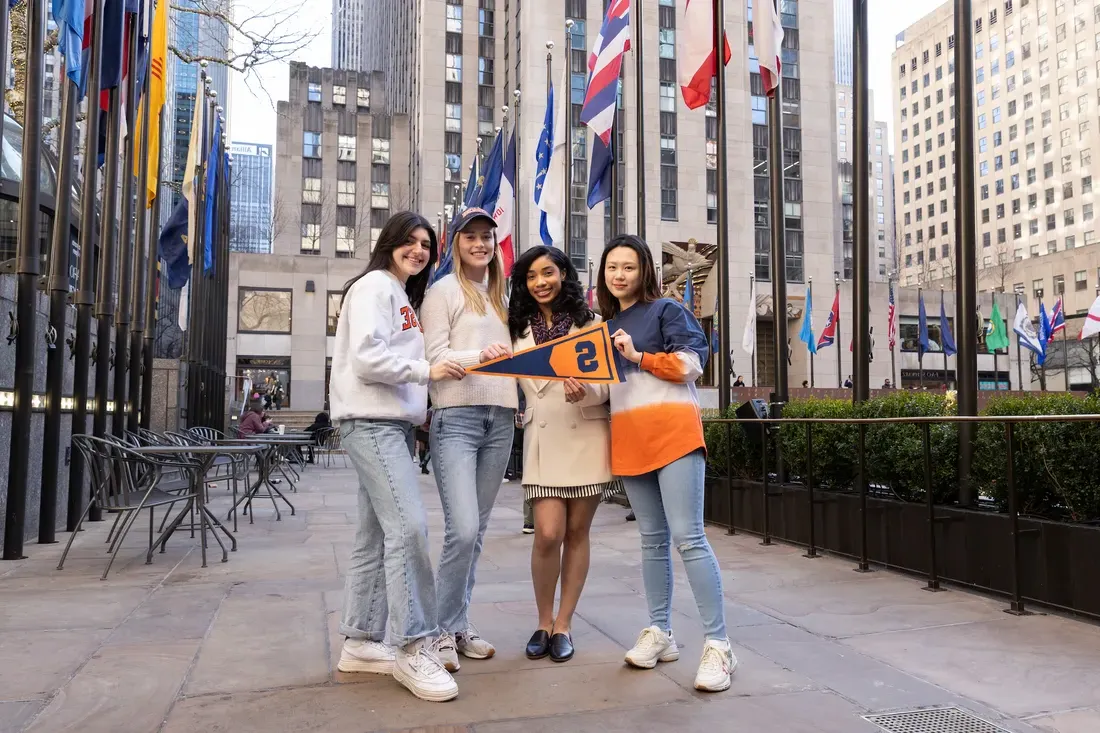 A group of people standing in NYC with a Syracuse University flag.